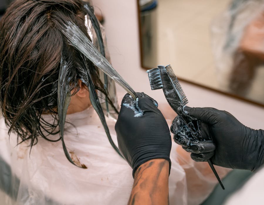Cabeleireira a aplicar coloração no cabelo com pincel profissional