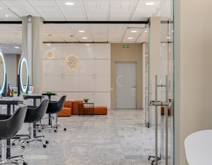 Interior moderno de salão de cabeleireiro com cadeiras e espelhos iluminados