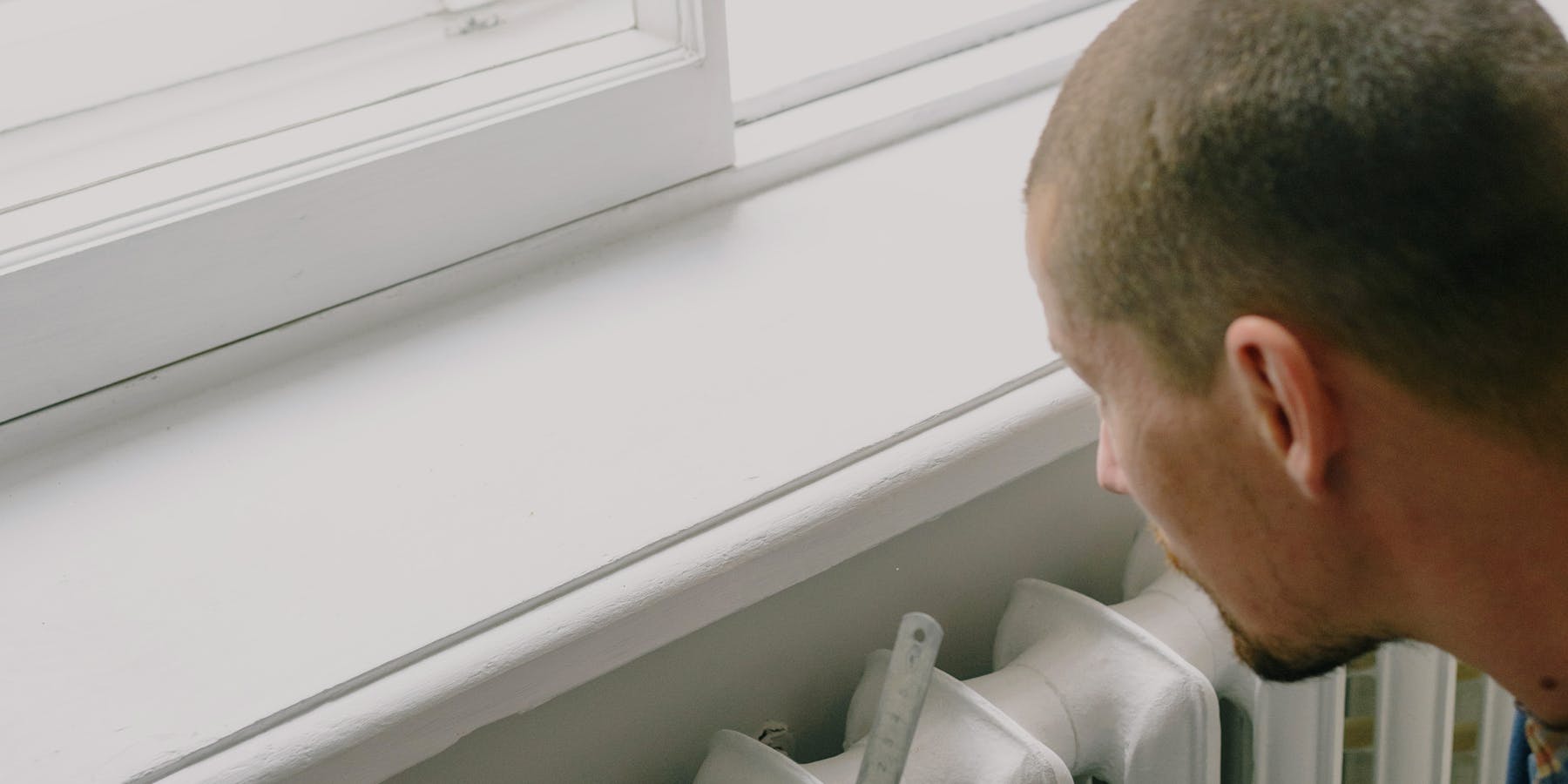 Técnico a inspecionar radiador de aquecimento em apartamento