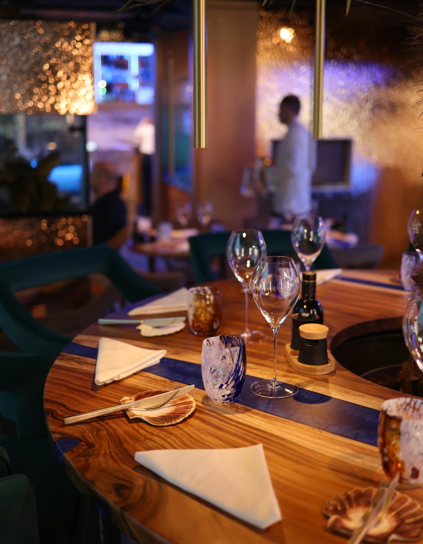 Interior de restaurante de serviço completo com mesa preparada e empregado ao fundo