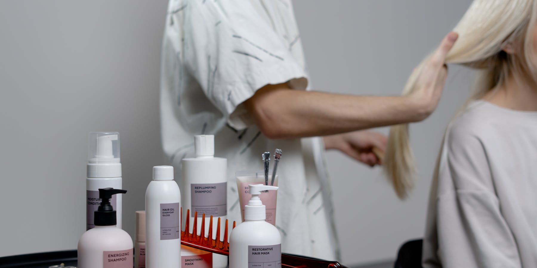 Cabeleireira a tratar do cabelo de uma cliente com produtos profissionais