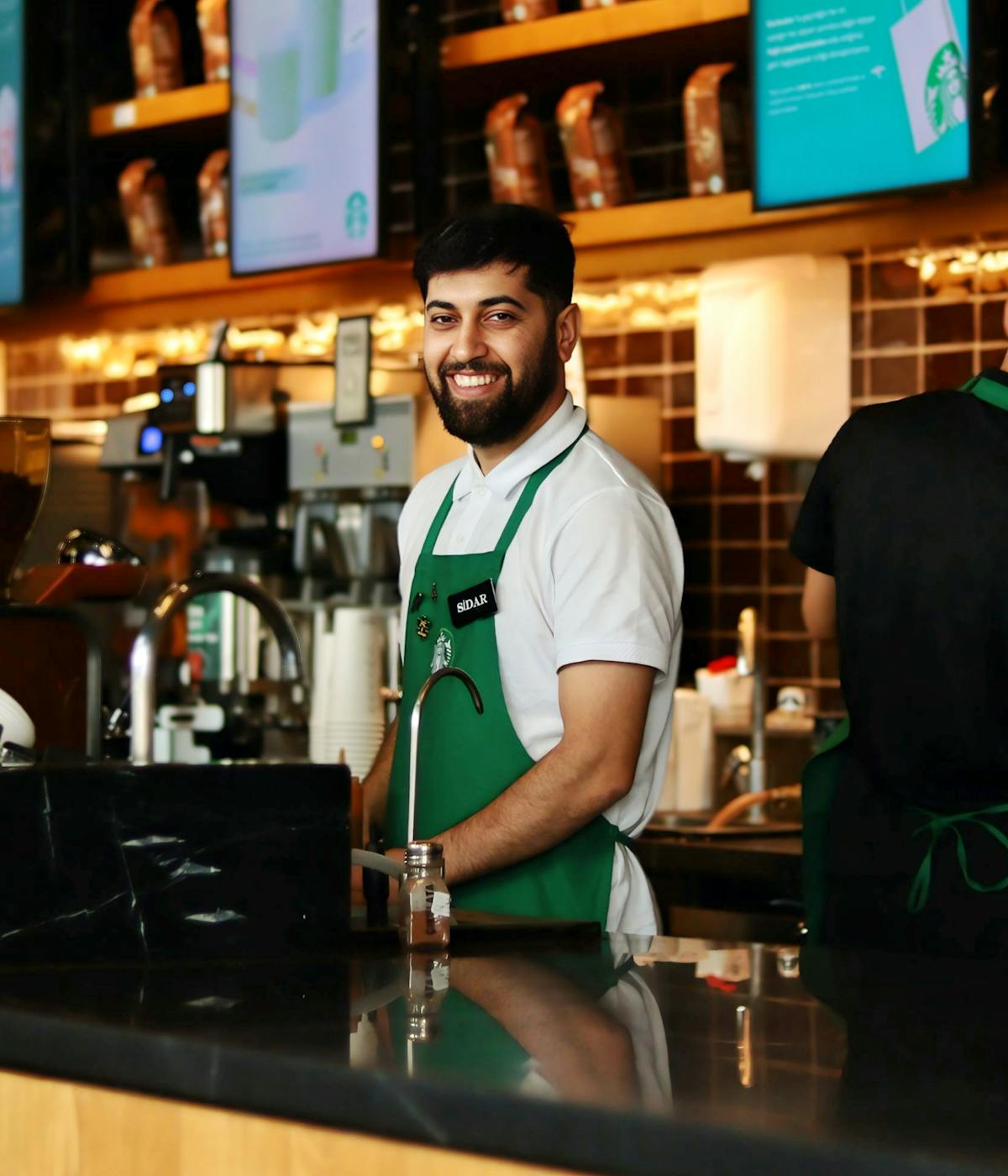 Empregado de balcão sorrindo com PDA na mão